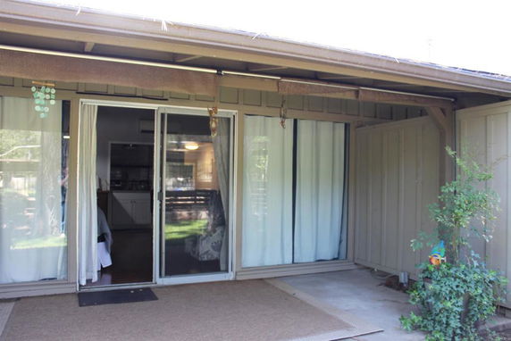 Front view of a house with sliding glass doors and curtains.