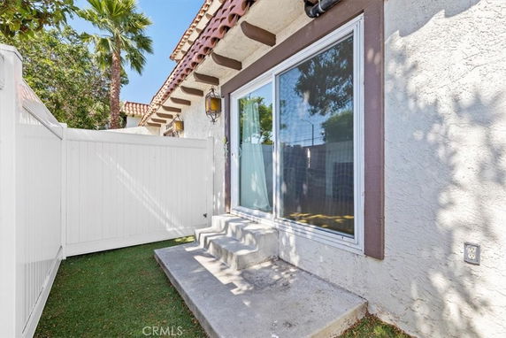 View of a building's exterior with large sliding glass doors and adjacent small patio area.