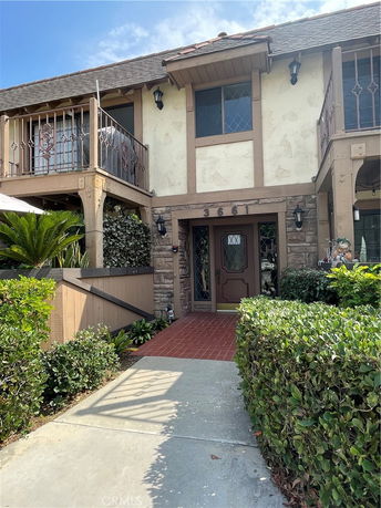Front view of a two-story house with decorative railings and a tiled entrance path.