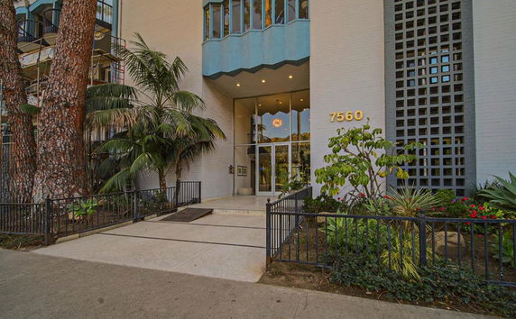 Front view of a multi-story building entrance with tall windows and a number sign.