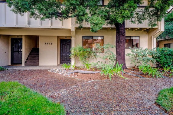 Front view of a two-story residential building with an entryway and trees.