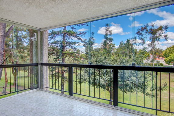 Panoramic view of trees and sky from a balcony with glass railings.