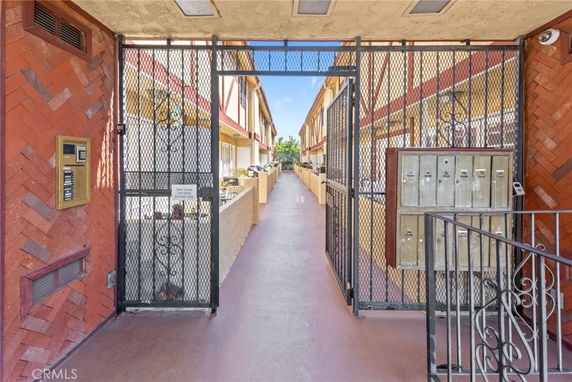 Front view of a multi-story apartment building entrance with metal gates and a row of mailboxes.