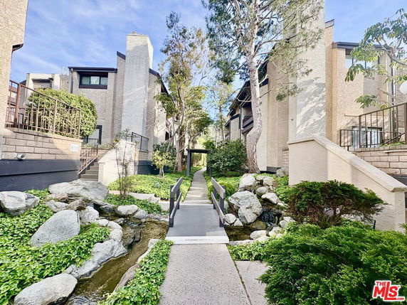 Front view of a multi-story residential building with a pathway and greenery.