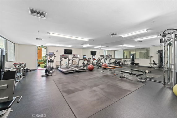 Interior of a gym area with exercise equipment including treadmills, ellipticals, and weight benches.