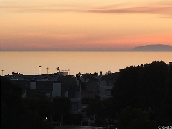 Panoramic view of the ocean at sunset with buildings in the foreground.