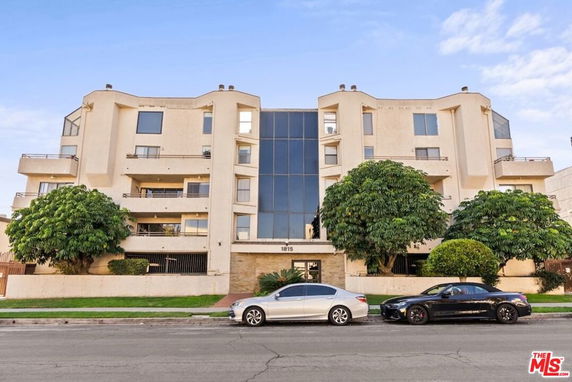 Front view of a multi-story residential building with large windows and balconies.