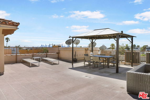 Rooftop patio area with seating and umbrellas, with city skyline in the distance.