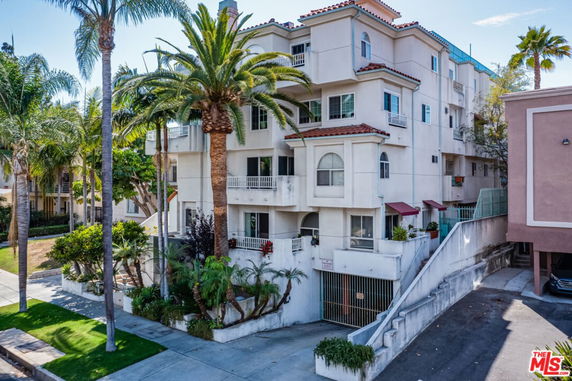 Front view of a multi-story residential building with balconies and a gated entrance.
