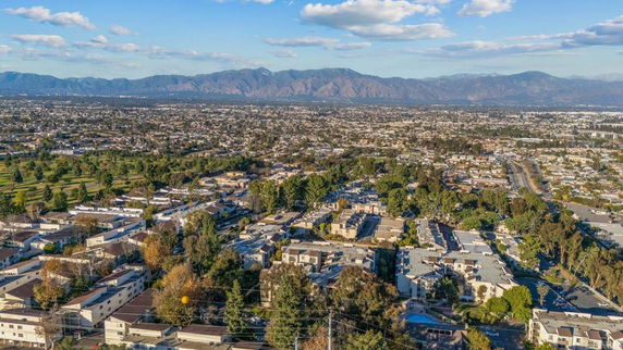 Panoramic aerial view of a city with residential buildings and mountains in the background.