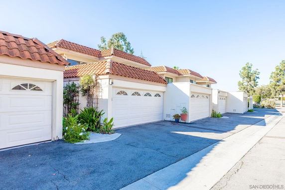 Front view of a row of townhouses with white garages and red-tiled roofs.