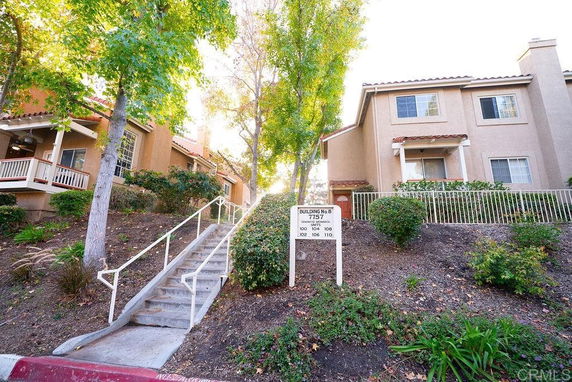 Front view of a multi-story residential building with a staircase leading to the entrance.