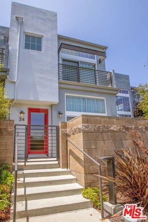 Front view of a modern multi-story house with a red door and balcony.