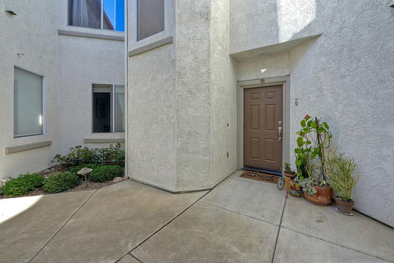 Entrance of a building with brown door and white textured walls.