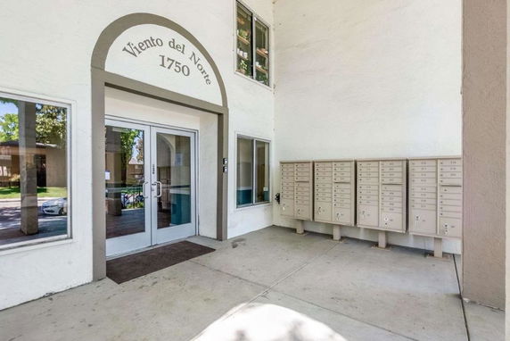 Elevated entryway of a building with glass doors and a set of mailboxes.