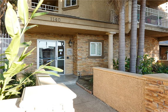 Front view of a building with stone facade and glass entrance door.