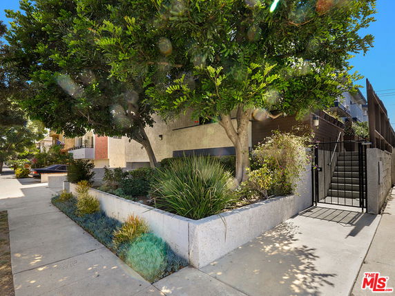Front view of a building with a gated entrance and surrounding greenery.