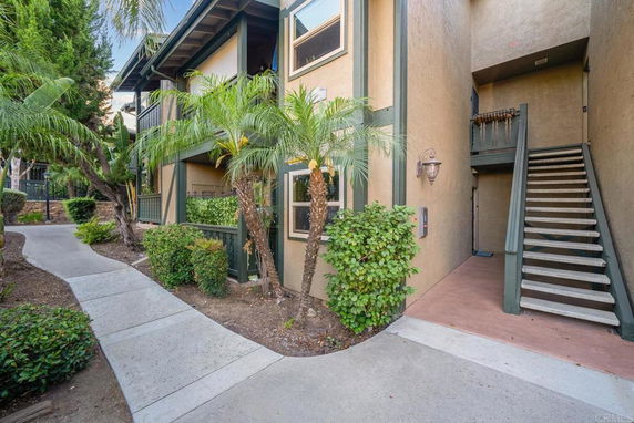 Front entrance of a two-story residential building with stairs and green trim.