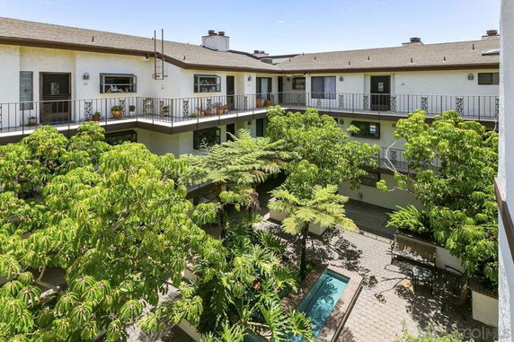 Courtyard view with greenery and a two-story apartment complex.