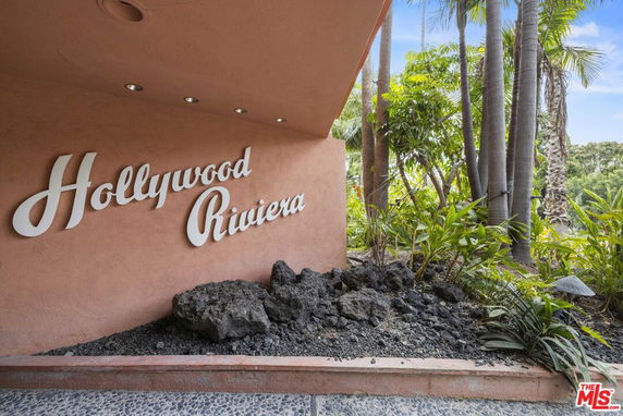 Front view of a building with 'Hollywood Riviera' sign and adjacent greenery.
