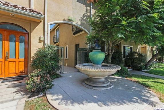 Front view of a building with an archway entrance and a decorative fountain.