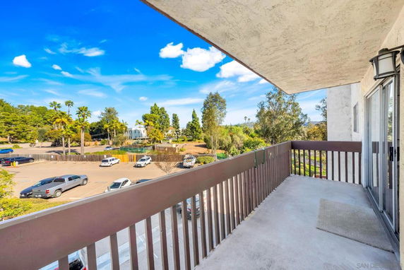 Balcony view overlooking a parking area and surrounding trees.