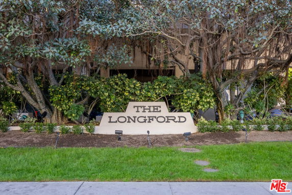 View of building entrance with 'The Longford' sign surrounded by greenery.