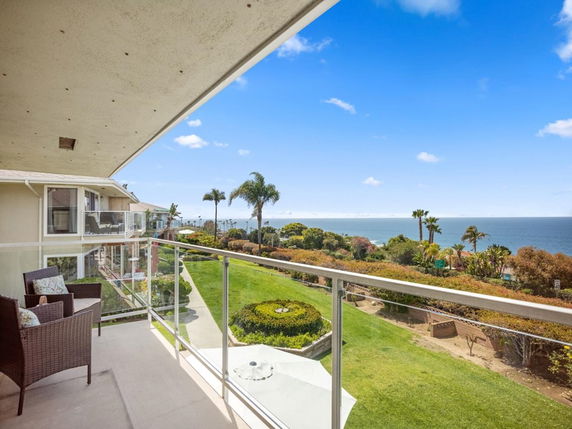 View from a balcony overlooking the ocean and surrounding greenery.