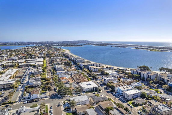 Panoramic aerial view of a coastal neighborhood with buildings and a body of water.
