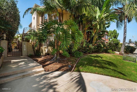 Front view of a house with a gated entrance and surrounding greenery.