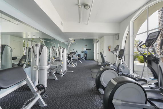Indoor gym area with various exercise equipment and large windows.