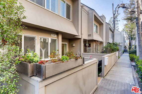 Front view of a multi-story residential building with a small garden area.