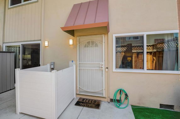 Front view of a house entrance with a small fenced area and window.