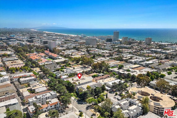 Aerial panoramic view of a coastal city with numerous buildings and the ocean in the background.