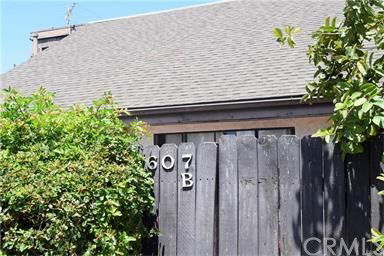 Front view of a house with a tall wooden fence and sloped roof.