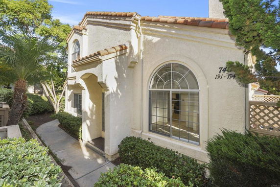 Front view of a multi-story house with arched windows and a tiled roof.