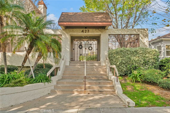 Front view of a house with steps leading to a gated entrance.