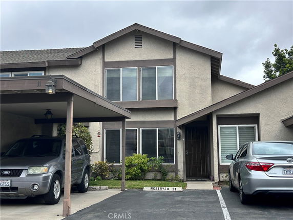 Front view of a two-story house with an attached carport and reserved parking space.