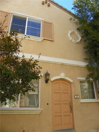 Front view of a two-story house with arched door and windows with shutters.