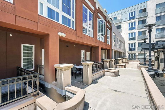 Front view of a multi-story building with large windows and a shared patio area.