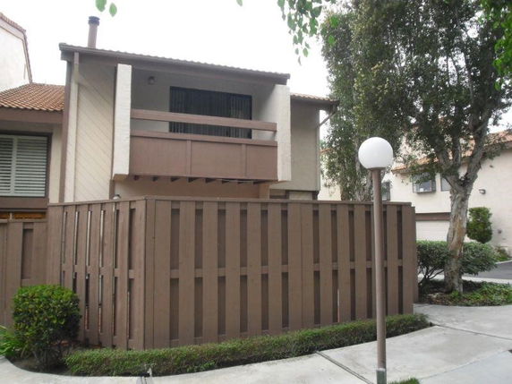 Front view of a two-story house with a fenced patio and a balcony.