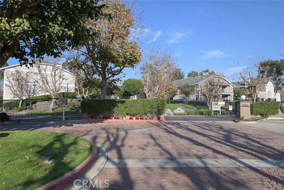 Gated entrance of a residential community with multiple houses visible.