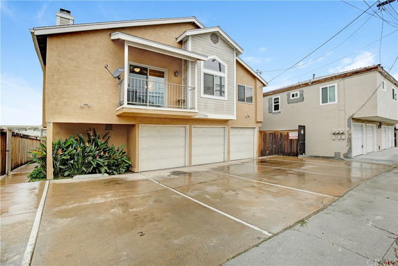 Front view of a two-story house with a balcony and three garages.