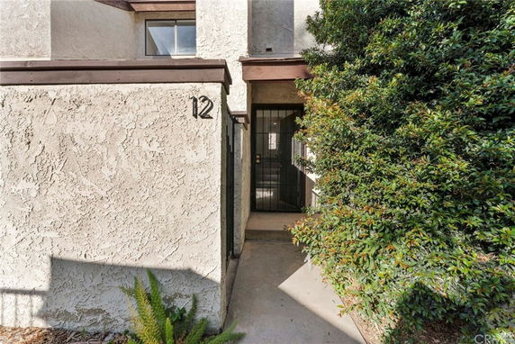 Entrance view of a building with textured walls and a gated door, marked with number 12.