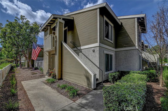 Front view of a two-story residential building with exterior stairs and a small balcony.