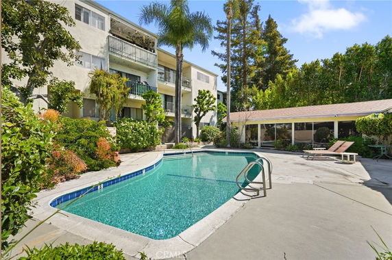 Outdoor swimming pool area with apartment building in the background.