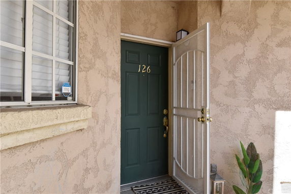Front view of an entrance door with a security gate and window, numbered 126.