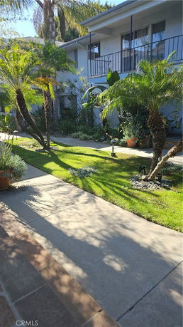 Front view of a house with a paved walkway and landscaped garden.