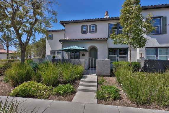 Front view of a two-story house with arched entrance and patio umbrella.
