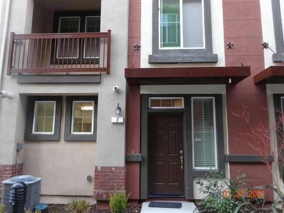 Front view of a multi-story house with a balcony and multiple windows.